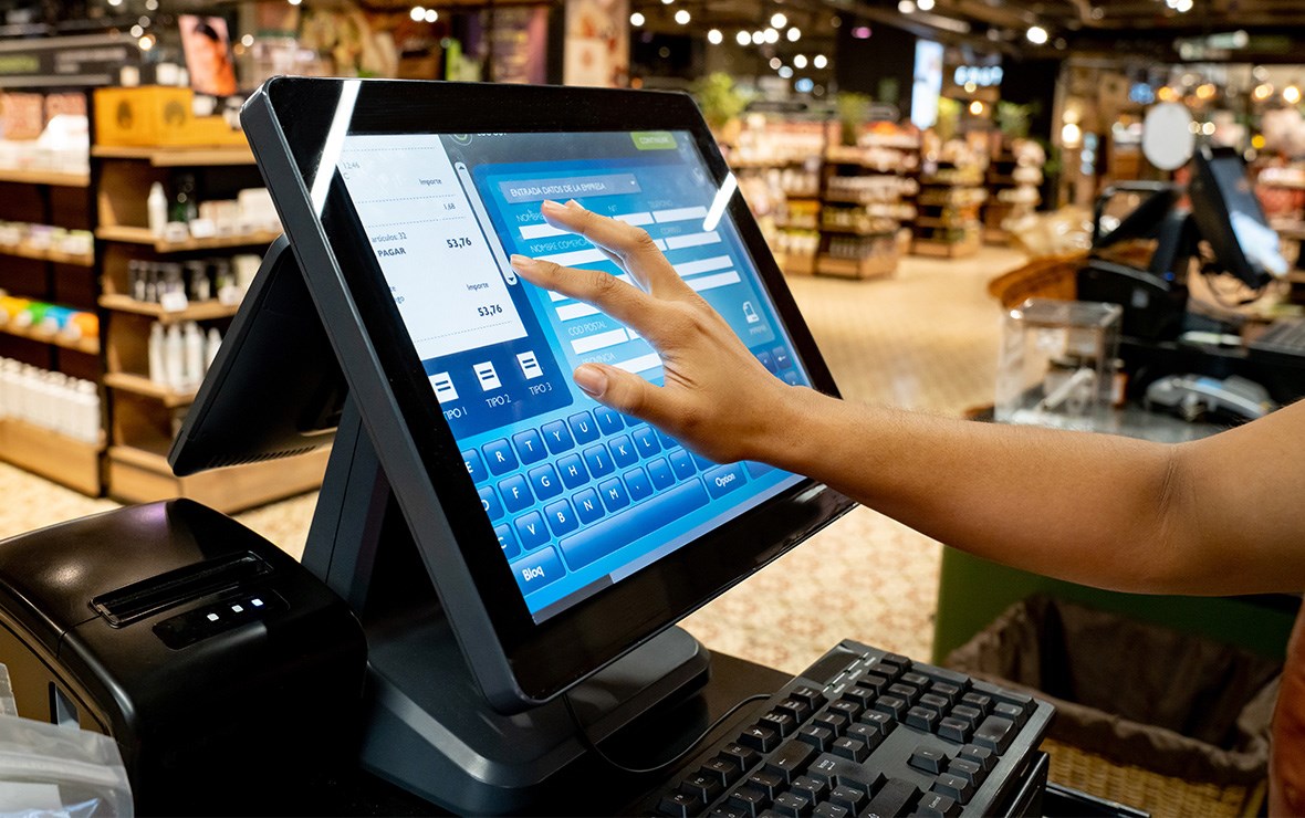 Main touchant un écran tactile dans un magasin.